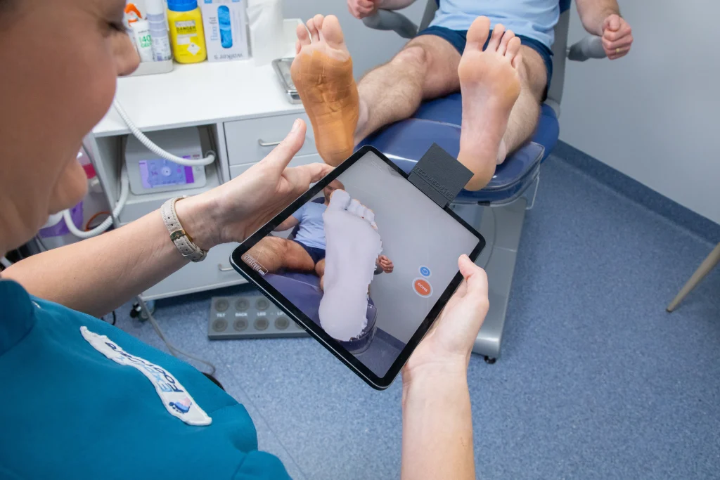 Podiatrist performing a 3D foot scan to assess biomechanics for custom orthotics and personalised foot care.